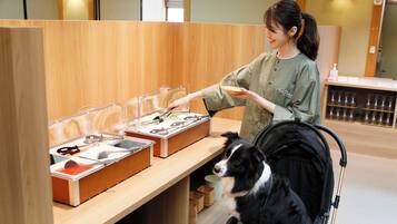 Una persona sirve comida de un bufé con un perro a su lado.