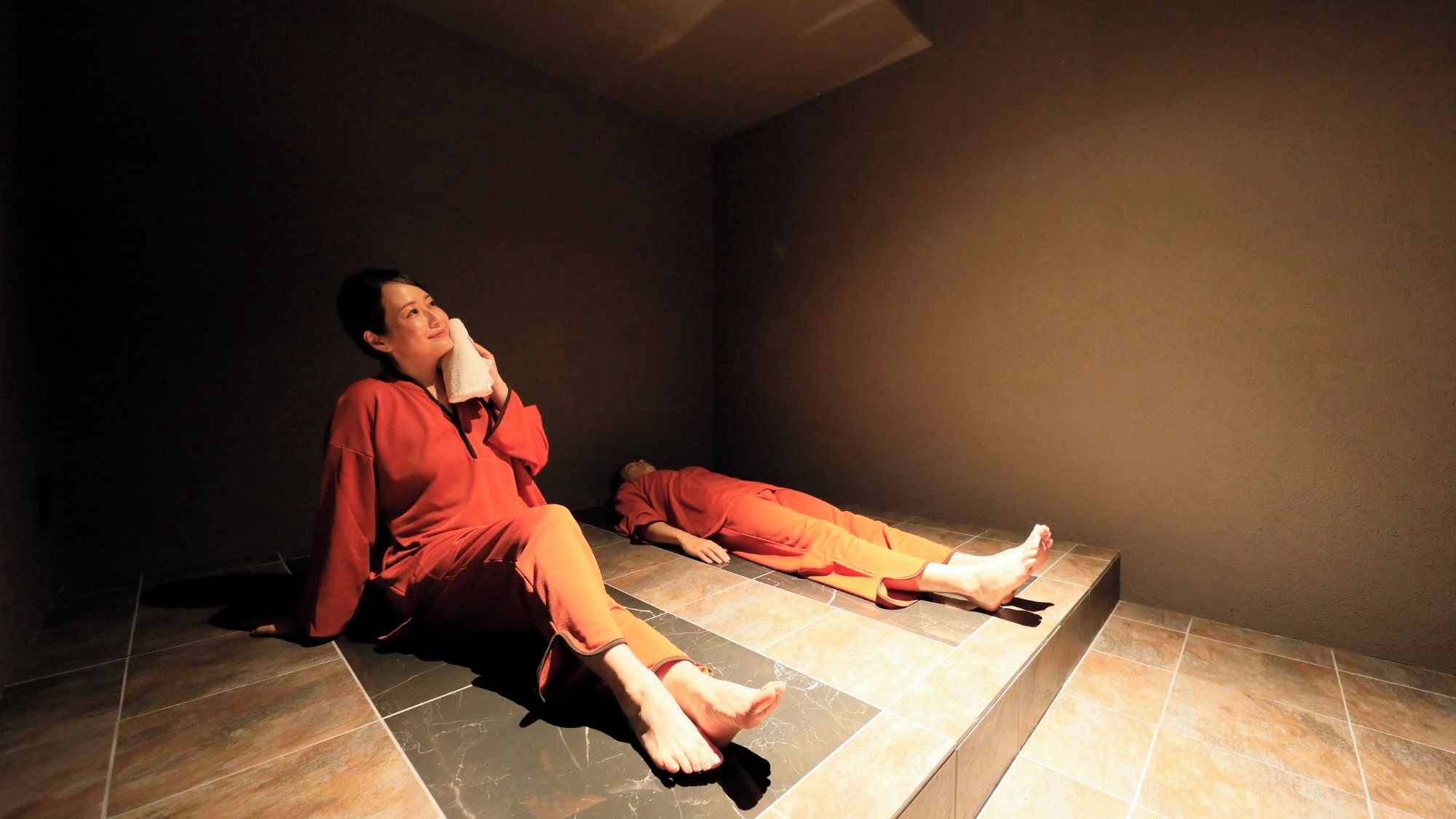 A room with a tiled floor and a person lying on the floor.