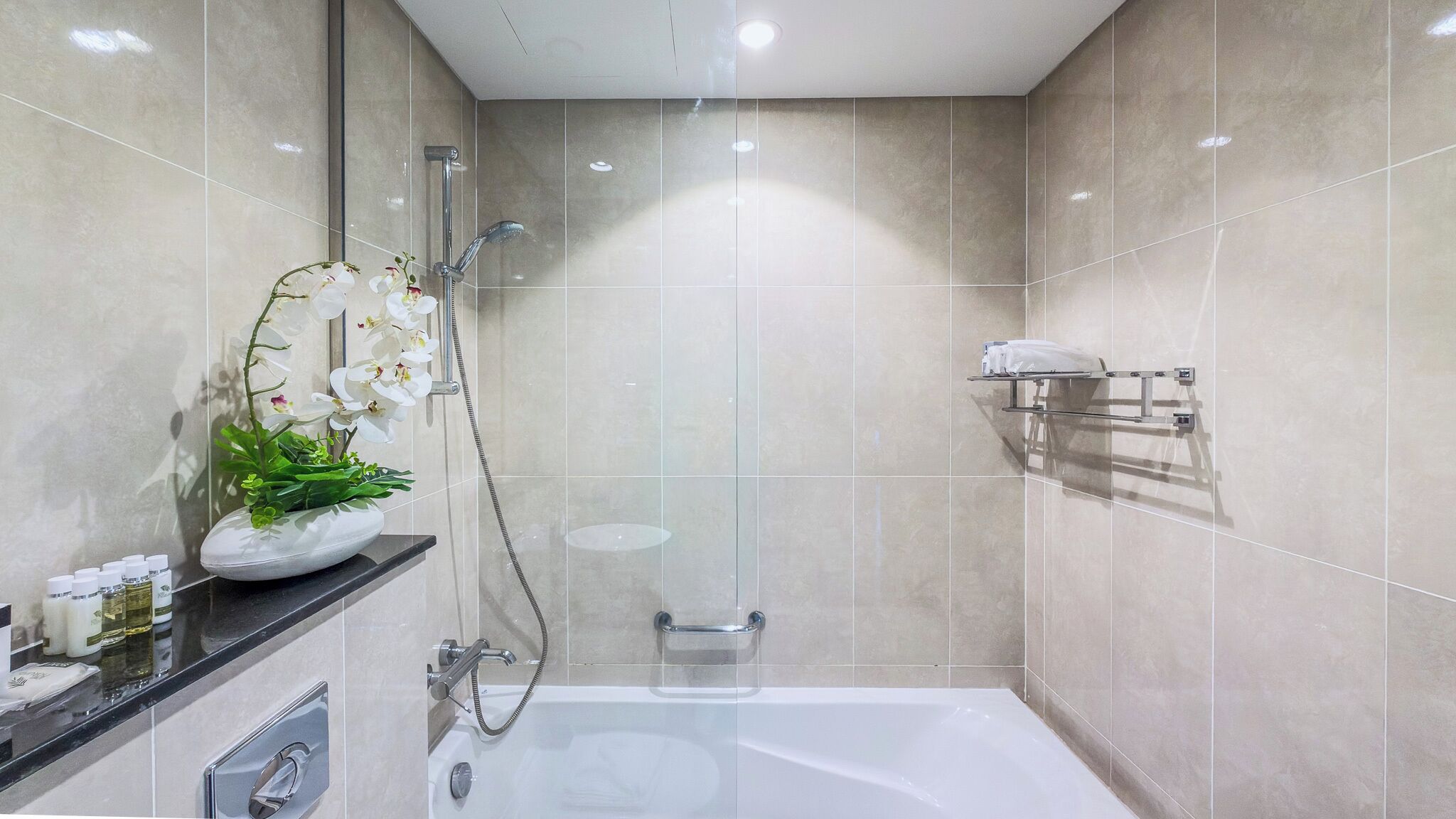 A modern bathroom with a bathtub, shower, and a vanity with toiletries.