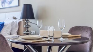 Ein ordentlich gedeckter Esstisch mit Tellern, Besteck und Gläsern, eine Lampe und eine Couch im Hintergrund.
