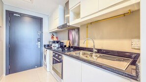 A compact kitchen with a built-in washer, a stove, and a sink. - Artesia Tower Residences - Damac Hills  (Dubai)