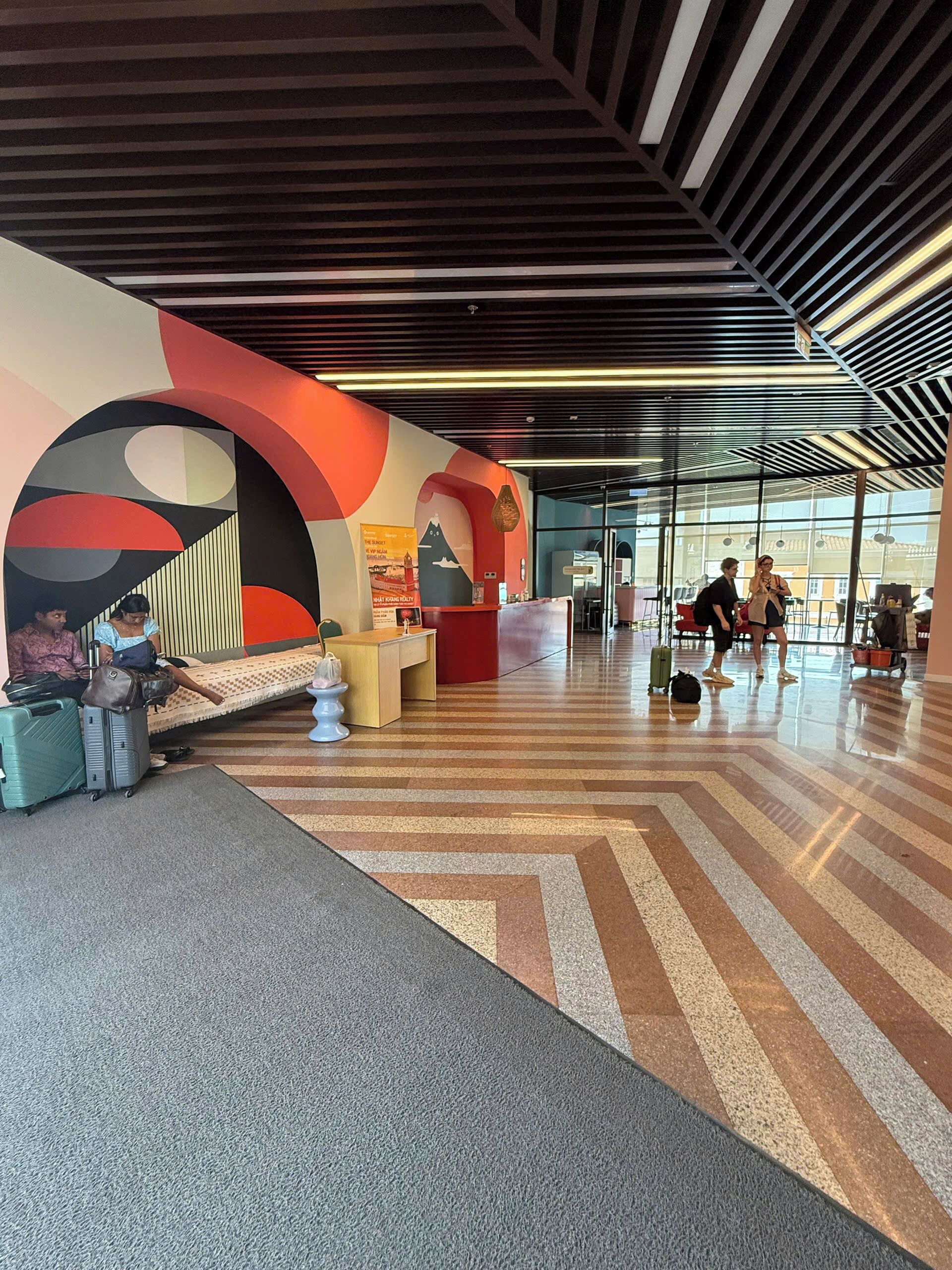 Un lobby espacioso con un diseño moderno, que incluye una recepción, zona de estar y espacio para equipaje.