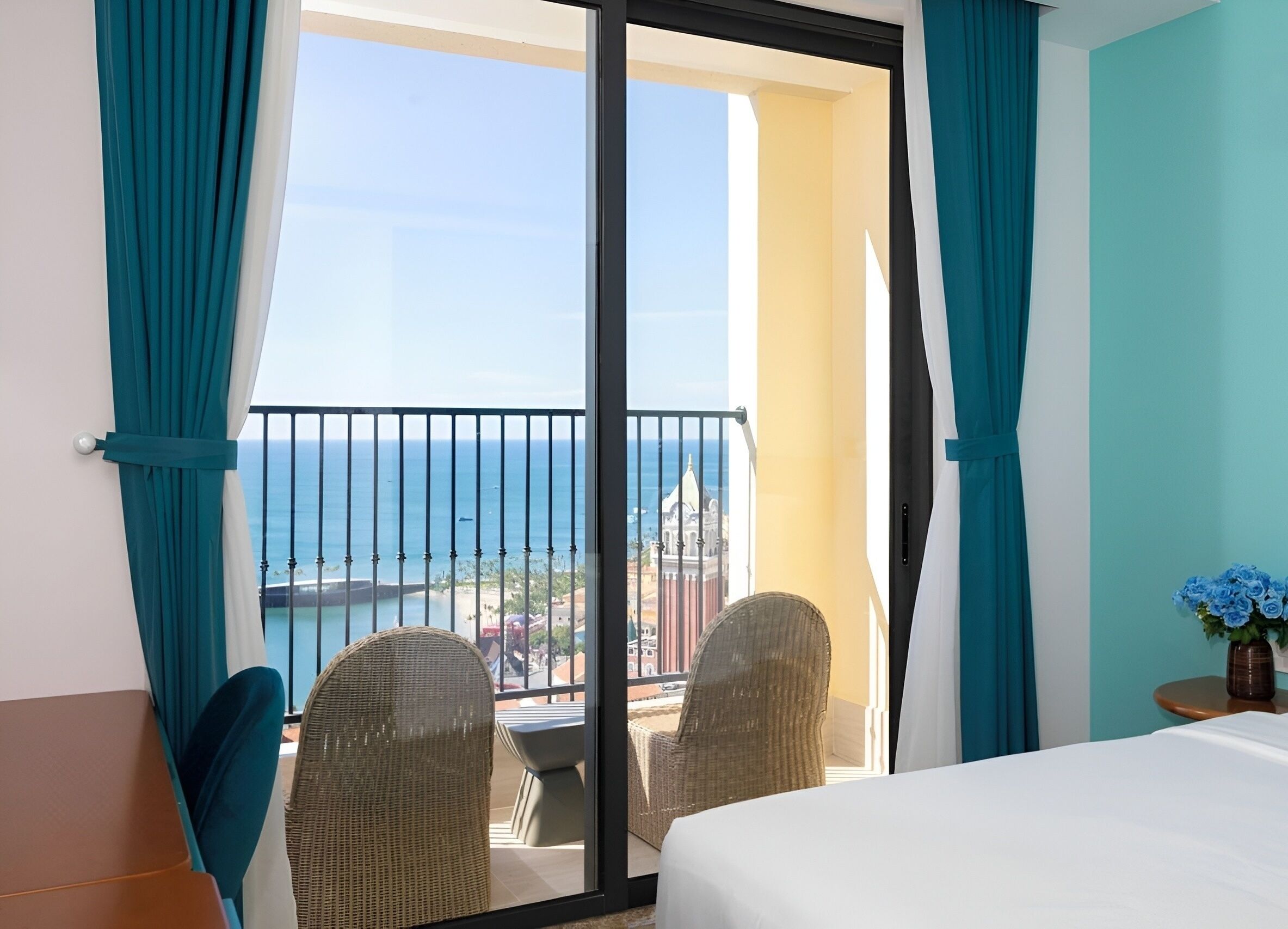 Una habitación de hotel con balcón, cama, mesa y sillas.