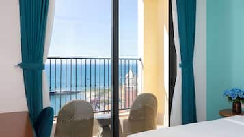 Una habitación de hotel con balcón, cama, mesa y sillas.