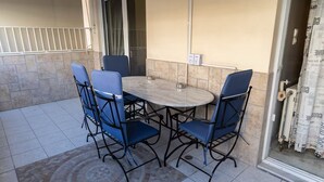 A patio with a round table and four chairs, a tiled floor, and a door leading to a balcony. - Coastal Haven οf Piraeus - by ΜΡS (Pireas)