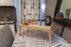 Een kleine kitchenette met een houten tafel, een doos Zaxaph en een koffiezetapparaat.