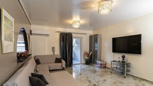 A modern living room with a sofa, a TV, and a glass coffee table. - Coastal Haven οf Piraeus - by ΜΡS (Pireas)