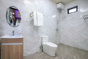 Un baño moderno con pared de mármol, inodoro, lavamanos y ducha.