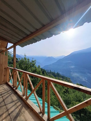 A wooden balcony with a view of a mountainous landscape.