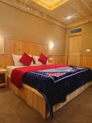 A wooden-paneled room with a bed, a nightstand, and a wall-mounted light fixture.