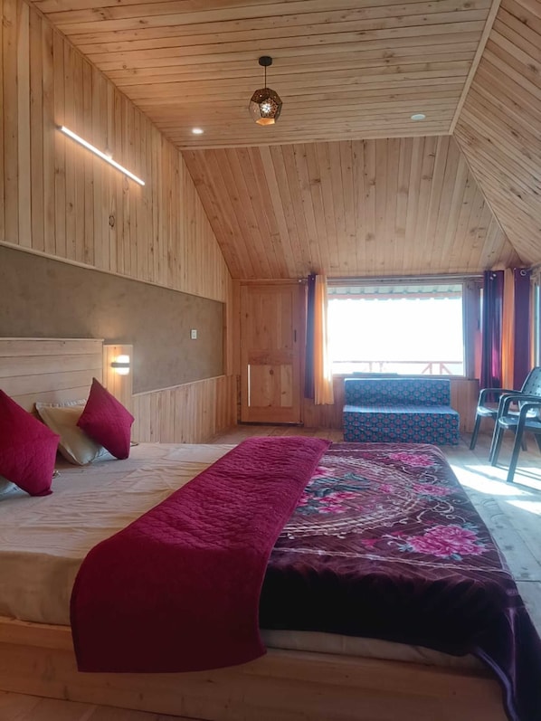 A wooden cabin bedroom with a bed, pillows, a bench, and a view of the outdoors.