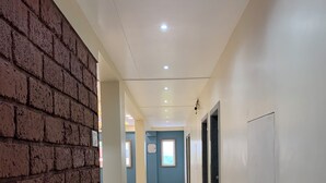 Un pasillo con pared de ladrillo a un lado, piso de baldosas e iluminación empotrada en el techo.