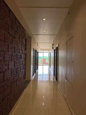 A corridor with a brick wall on one side and a plain wall on the other, leading to a bright exit.