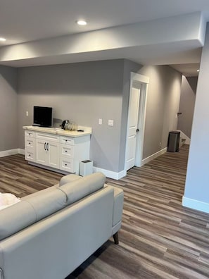 A modern living room with a sofa, a flat-screen TV, and a white entertainment unit.