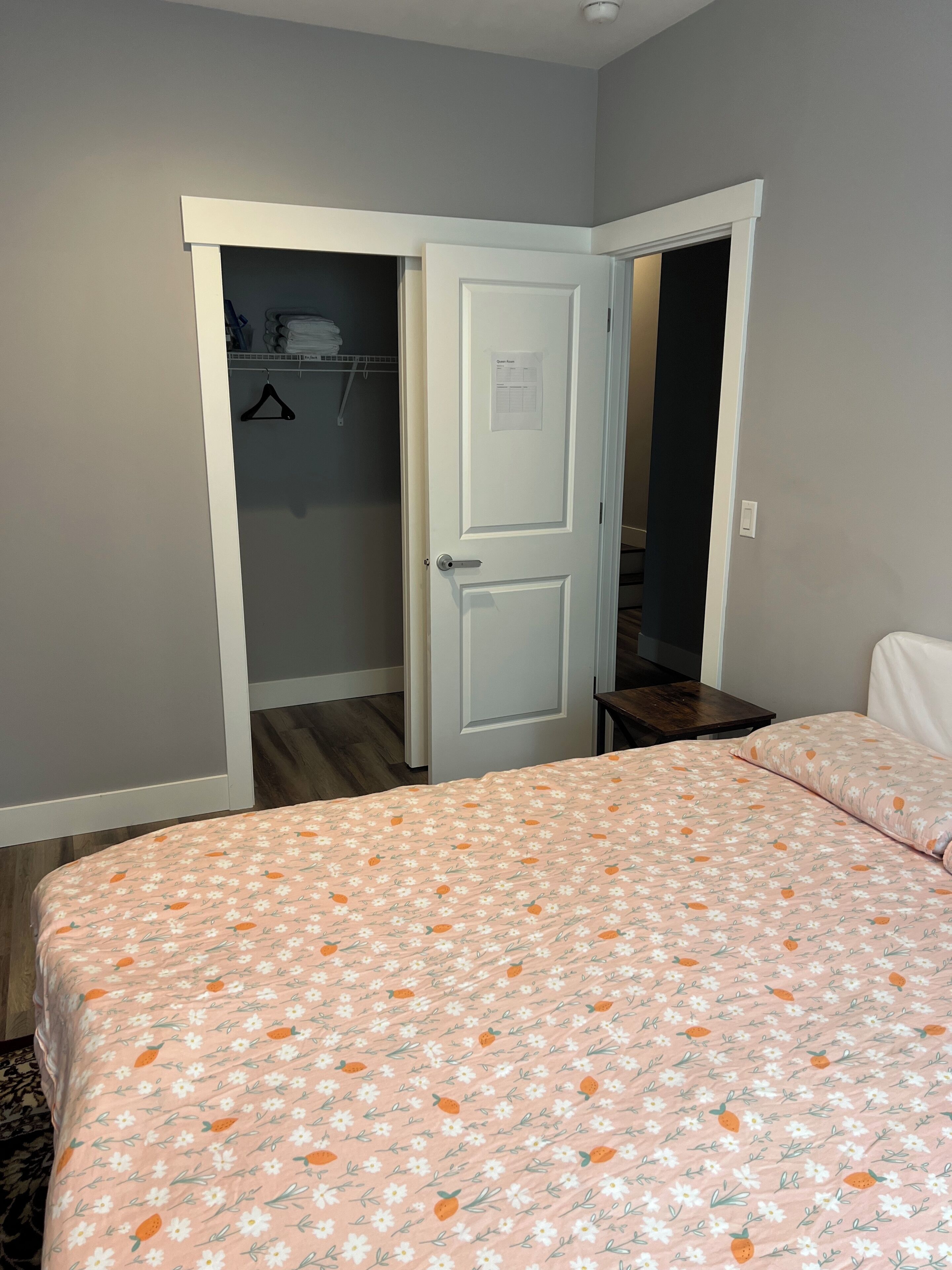 Een slaapkamer met een bed, een kledingkast en een deur naar een andere kamer.