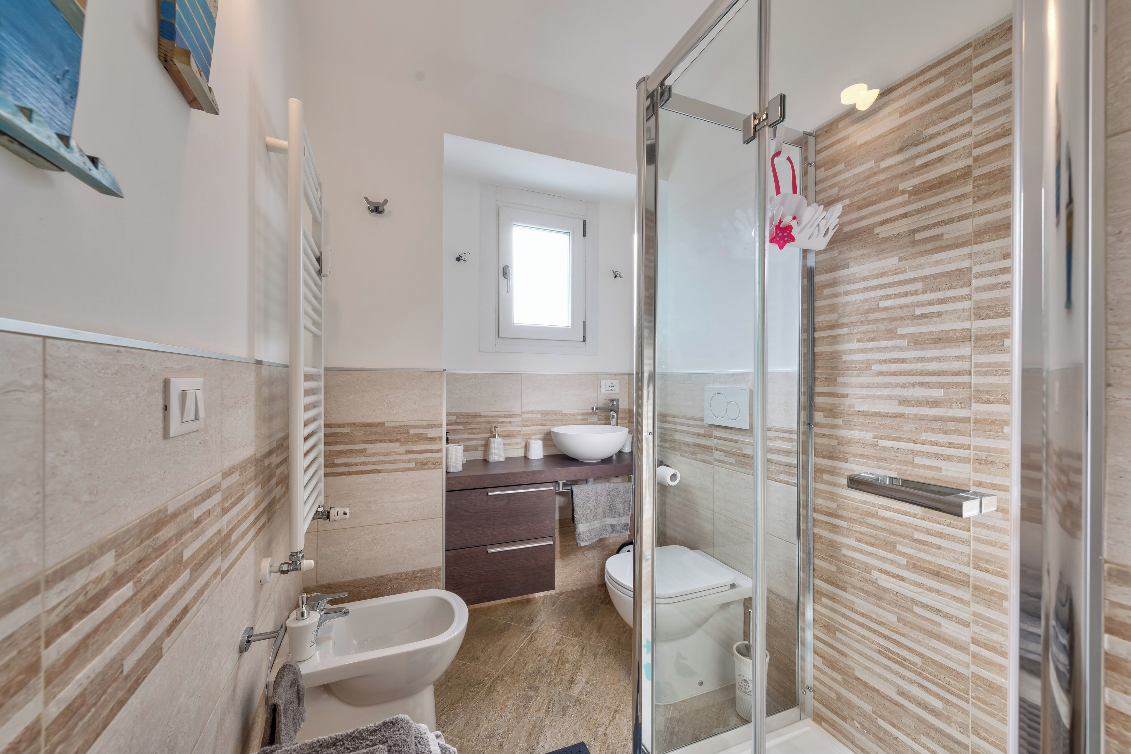 A modern bathroom with a glass shower enclosure, a bidet, a sink, and a toilet.