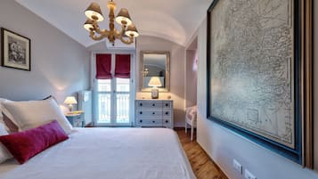 Una camera da letto con un letto grande, un lampadario, una cassettiera, uno specchio e una mappa appesa al muro.