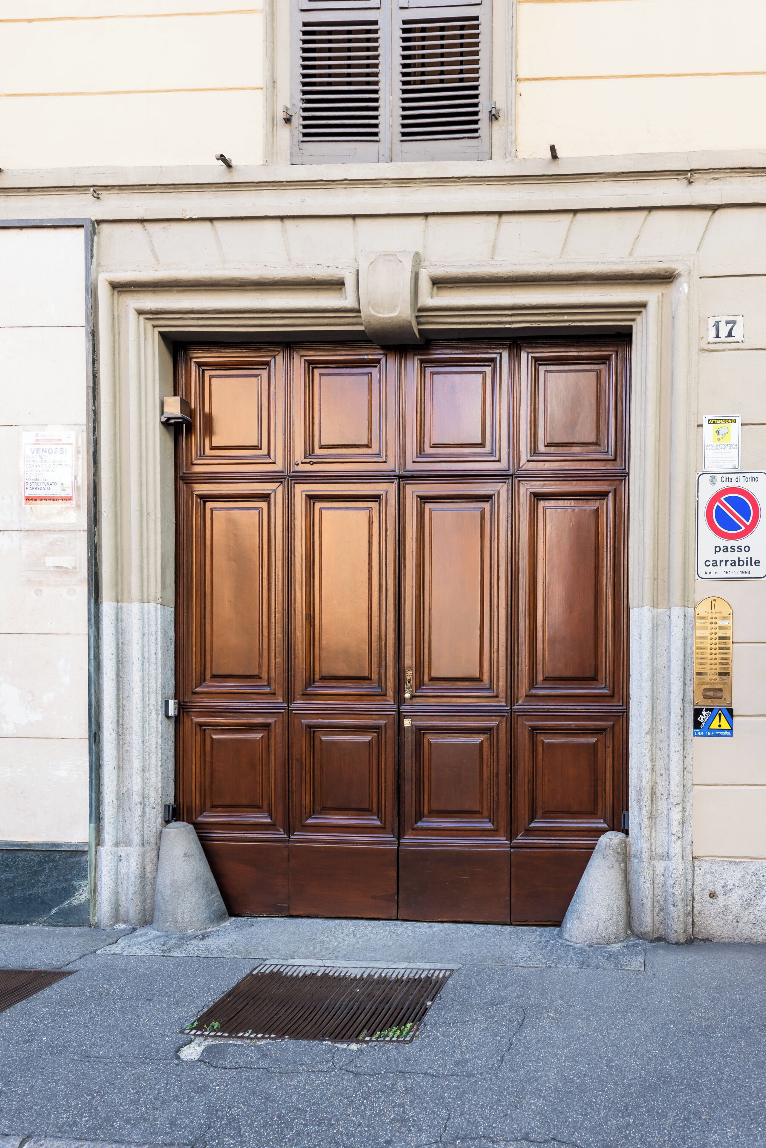 Un'ampia porta in legno intagliata, con il numero '17' sopra, incastonata in una facciata color beige.