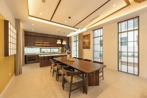 Una cocina moderna con una isla central, una zona de comedor con una mesa grande y ventanas amplias que dejan entrar luz natural.