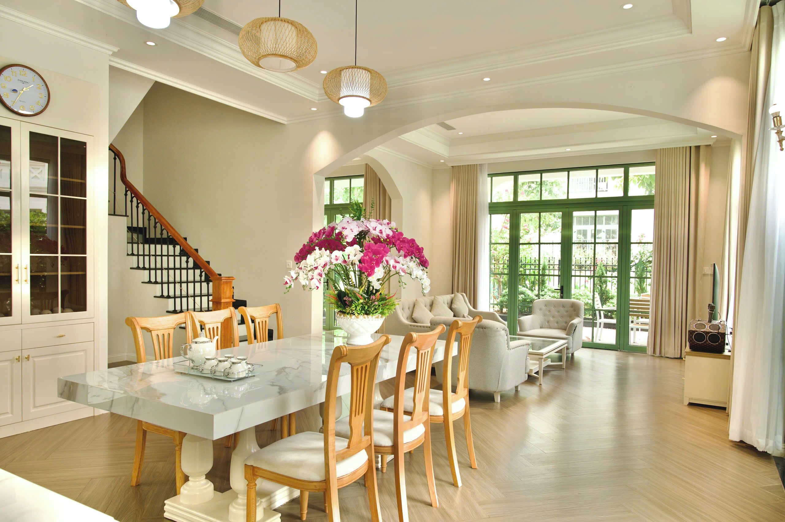 A spacious dining area with a marble table, wooden chairs, and a large floral centerpiece.