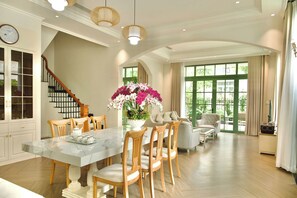 Un comedor amplio con una mesa de mármol, sillas de madera y un gran centro de mesa floral.