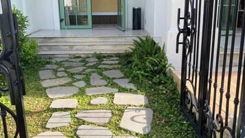 Un vialetto conduce all'ingresso di un edificio con una porta verde e un cancello in ferro battuto nero.
