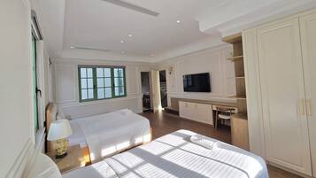 Una camera d'albergo con un letto, una scrivania con televisore e un armadio.