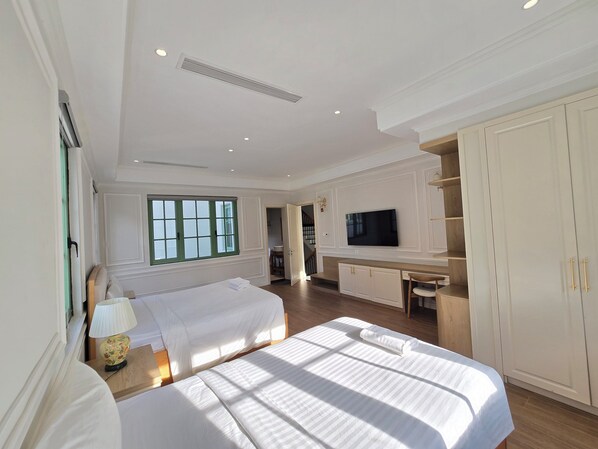 A hotel room with a bed, a desk with a television, and a wardrobe.