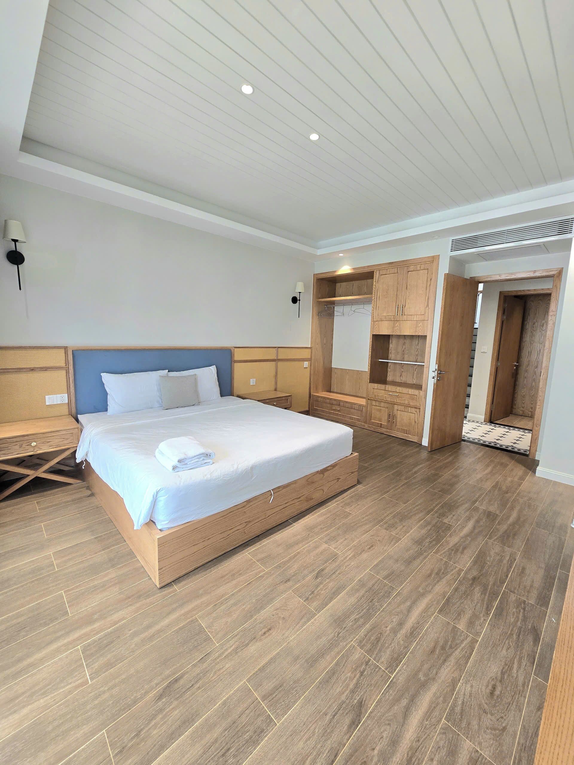 A spacious bedroom with a large bed, wooden wardrobe, and a walk-in closet.