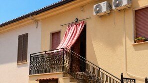 A building with a balcony, a red and white striped awning, and two air conditioning units.