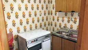 Uma cozinha compacta com fogão branco, pia e armários de madeira.