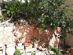 A stone wall with potted plants and a small statue. - Aloe Villa Chania Crete (Georgioupoli Exopoli Crete)