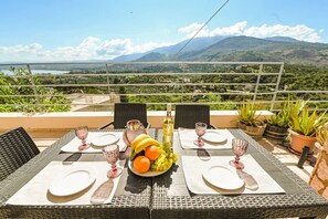 A table set for two with a fruit bowl, wine glasses, and a bottle, overlooking a mountainous landscape. - Aloe Villa Chania Crete (Georgioupoli Exopoli Crete)