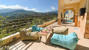 Eine Terrasse mit Sitzgelegenheiten im Freien, einem Pool und Blick auf Berge.