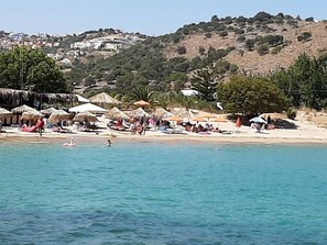 A beach with thatched-roof huts, a sandy shore, and a hilly backdrop. - Aloe Villa Chania Crete (Georgioupoli Exopoli Crete)