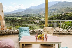 Een terras met een eettafel, met uitzicht op een bergachtig landschap.