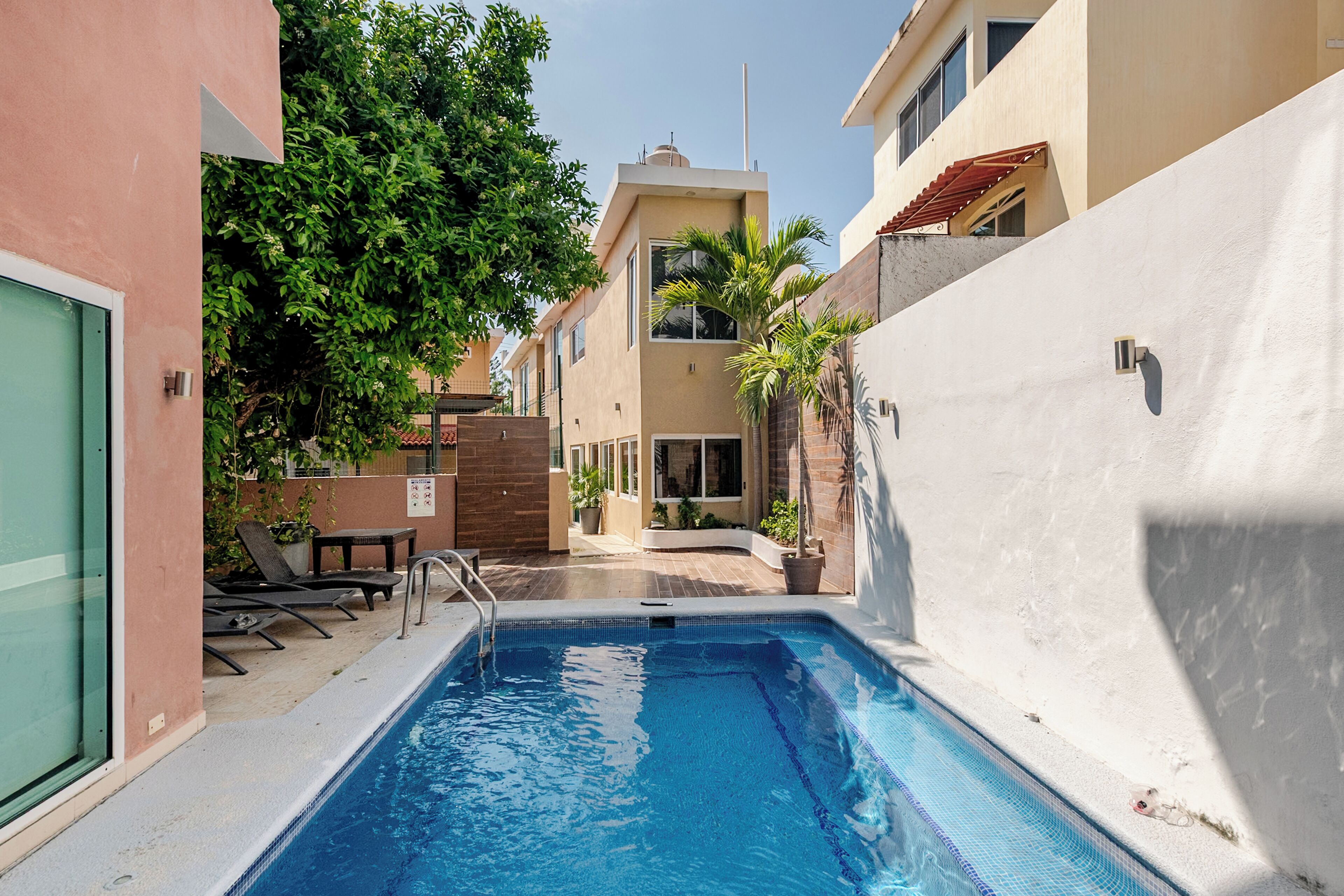 A swimming pool with a tiled deck, surrounded by buildings with balconies and windows.