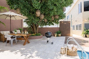 An outdoor patio with a dining table, chairs, a grill, and a poolside area. - Coral 55 · 3 blocks from Marina l La Cruz · Bathtub and pool (Cruz de Huanacaxtle)