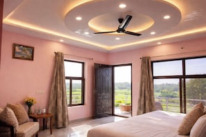 Ein Schlafzimmer mit einem Bett, einem Deckenventilator und großen Fenstern mit Vorhängen.