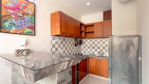 Una cocina con encimera de mármol, armarios de madera, salpicadero de cuadros y refrigerador de acero inoxidable.