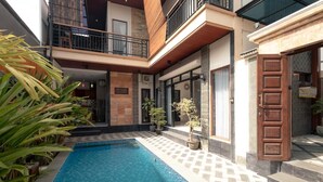 Un edificio moderno de dos pisos con piscina, mobiliario exterior y un balcón.