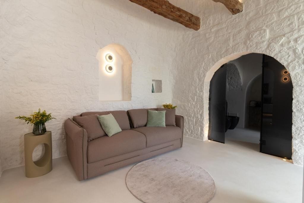 Un intérieur moderne avec un canapé beige, un tapis rond et un mur blanc à la texture intéressante.