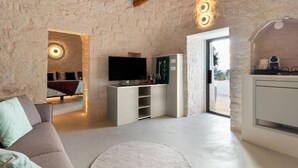 Un interior moderno con pared de piedra, televisión de pantalla plana, sofá y zona de comedor.
