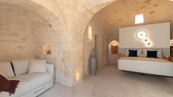 Una habitación con pared de piedra, un sofá, una cama y una lámpara moderna.