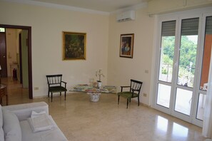 A spacious living room with a glass coffee table, two chairs, a sofa, and a balcony with a view. - Apartment in a Villa with a Spa (mezzanego)