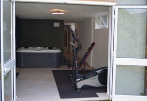 A room with a jacuzzi, exercise equipment, and a tiled floor. - Apartment in a Villa with a Spa (mezzanego)