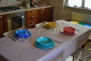 A kitchen with a dining table set for four, equipped with plates, glasses, and cutlery. - Apartment in a Villa with a Spa (mezzanego)