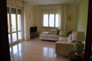 A living room with a sofa, a television, and a lamp. - Apartment in a Villa with a Spa (mezzanego)