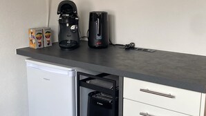 Ett litet kök med ett kylskåp från Bosch, en kaffebryggare och en brödrost.