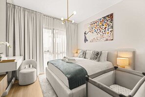 A modern hotel room with a large bed, a desk, a chair, and a painting on the wall. - StayShort | Stylish 1BR Apartment | Near Burj Al Arab | Family-Friendly | Sleeps 4 (Dubai)